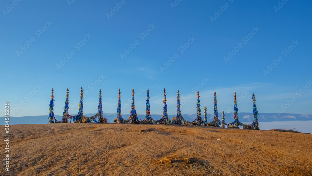Wooden ritual pillars with colorful ribbons on cape Burkhan, Lake Baikal, Olkhon island, Russia.