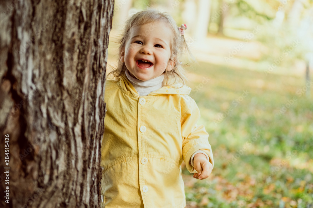 Caucasian child girl laughing walking in the park near a tree Caucasian child girl laughing walking in the park near a tree