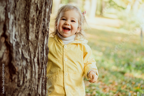 Caucasian child girl laughing walking in the park near a tree