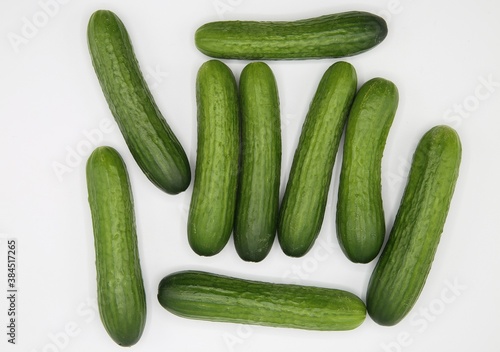 Top down view on isolated scattered group green raw fresh mini cucumbers on white blank background