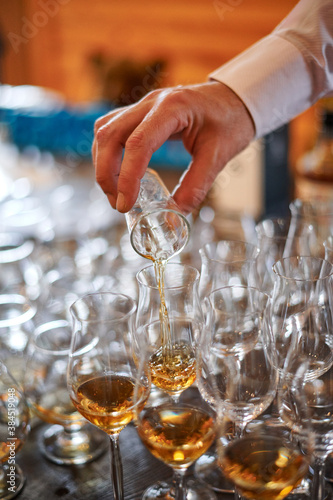 Tasting cognac or brandy. Glasses with brandy or cognac stand in a row. The waiter pours cognac into glasses, close-up