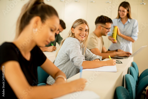 University students in the classroom with young female assistant lecturer