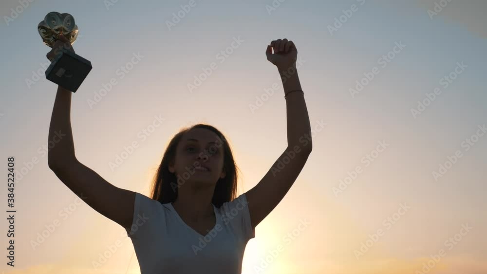 Happy girl winner jumps up and raises her hands with a cup above her head and celebrates the victory. The path to success is the highest happiness. Achievement award. The child is a winner. Happy girl winner jumps up and raises her hands with a cup above her head and celebrates the victory. The path to success is the highest happiness. Achievement award. The child is a winner.