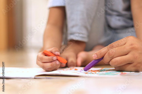 Asian muslim mother drawing with her daughter, single mom teaching baby girl, learning on the floor, happy family
