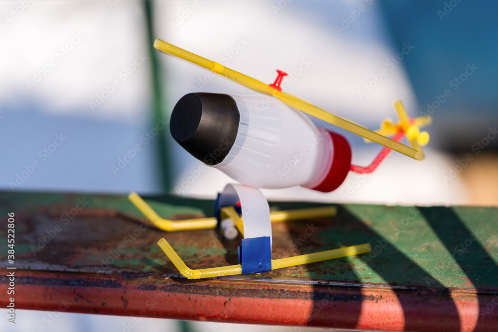 DIY toy helicopter made of waste and plastic bottles on snow background. Recycle crafts.