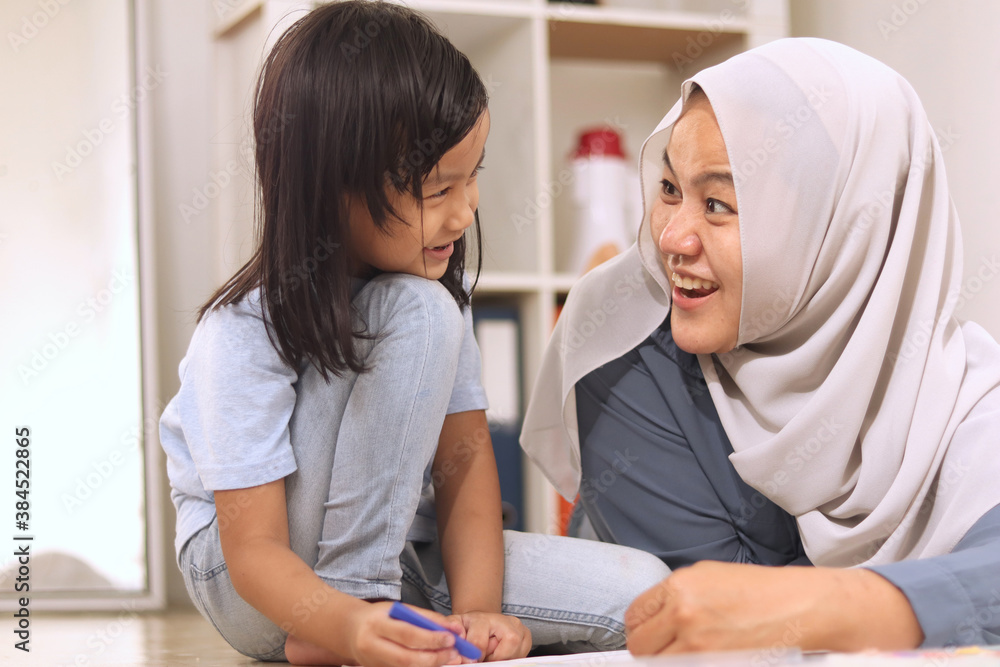 Asian muslim mother drawing with her daughter, single mom teaching baby girl, learning on the floor, happy family Asian muslim mother drawing with her daughter, single mom teaching baby girl, learning on the floor, happy family
