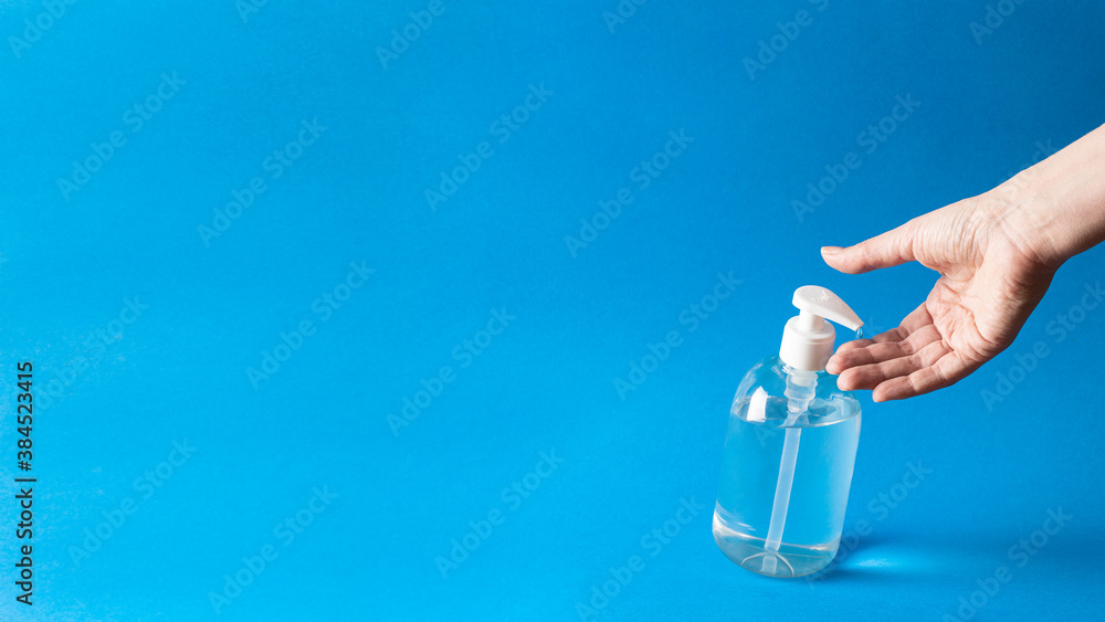 Naklejka premium Anti bacterial gel poured on hand on blue background.Large image with copy space