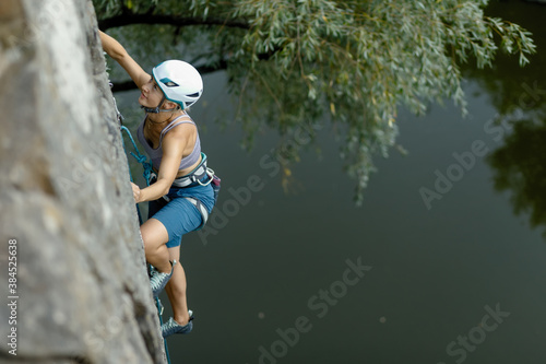 fitness, extreme sport and healthy lifestyle concept - Climber overcomes challenging climbing route. A girl climbs a rock. Woman engaged in extreme sport. Extreme hobby.