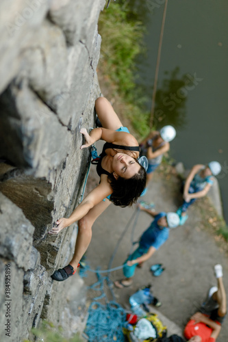 fitness, extreme sport and healthy lifestyle concept - Climber overcomes challenging climbing route. A girl climbs a rock. Woman engaged in extreme sport. Extreme hobby.