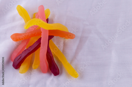 Colourful Gummy Jelly Snakes in tangle with copy space on white background
