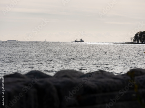 A silhouette of a small cargo vessel crossing the sunny horizon.
