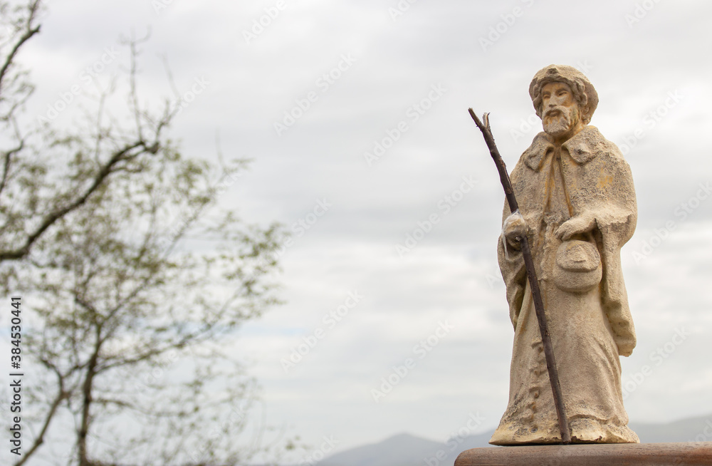 Small statue of Saint James on Camino de Santiago. Pilgrimage concept. Main christian saint of pilgrims. Ancient sculpture of Saint James in Pyrenees mountains, France. Religious architecture. 