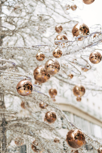 Gold glossy Christmas balls on a white glass Christmas tree.