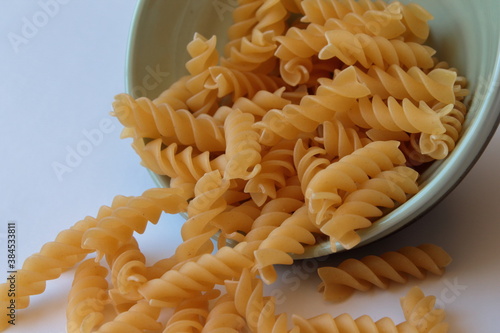 Raw uncooked pasta fusulli in ceramic bowl over white background