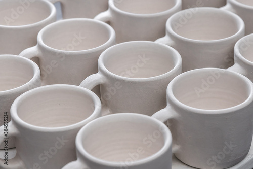 Many ceramic white cup pattern in the potters studio. Seamless abstract creative cover background, close-up. Minimal concept of creativity and art