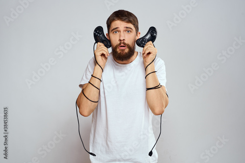 A man holds in his hands two joysticks playing leisure technology lifestyle white t-shirt