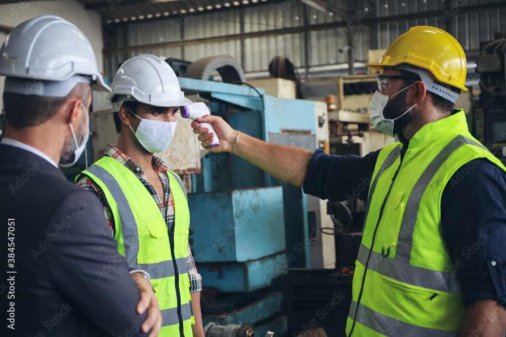 Supervisor use meter to measure temperature degree of employees or engineer before work in factory, Covid-19 screen and protection, team wear face mask while working in manufacturing Supervisor use meter to measure temperature degree of employees or engineer before work in factory, Covid-19 screen and protection, team wear face mask while working in manufacturing