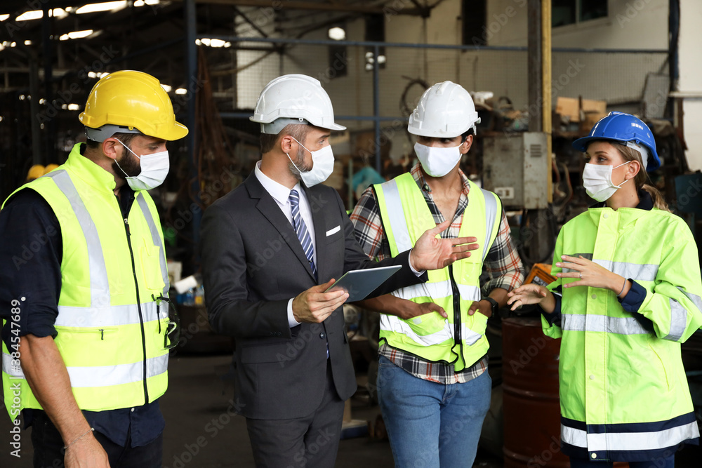 Leader or manager using tablet and meeting with engineer and technician while line walk in factory workplace, team wear face mask whine working at maintenance machine shop Leader or manager using tablet and meeting with engineer and technician while line walk in factory workplace, team wear face mask whine working at maintenance machine shop