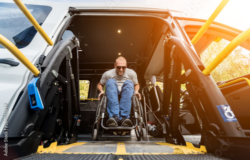 A man in a wheelchair on a lift of a vehicle for people with disabilities