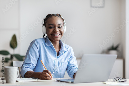 Black Female Student Studying Online With Laptop, Listening Music And Taking Notes