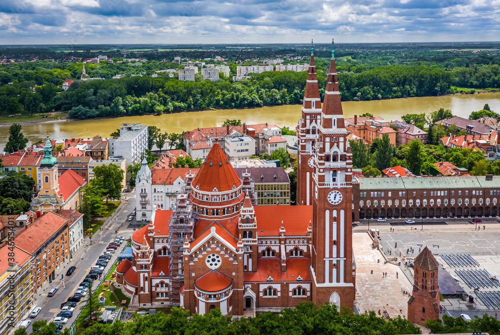 Fototapeta premium Szeged, Hungary - Aerial view of the Votive Church and Cathedral of Our Lady of Hungary (Szeged Dom) on a sunny summer day with River Tisza and blue sky and clouds at background