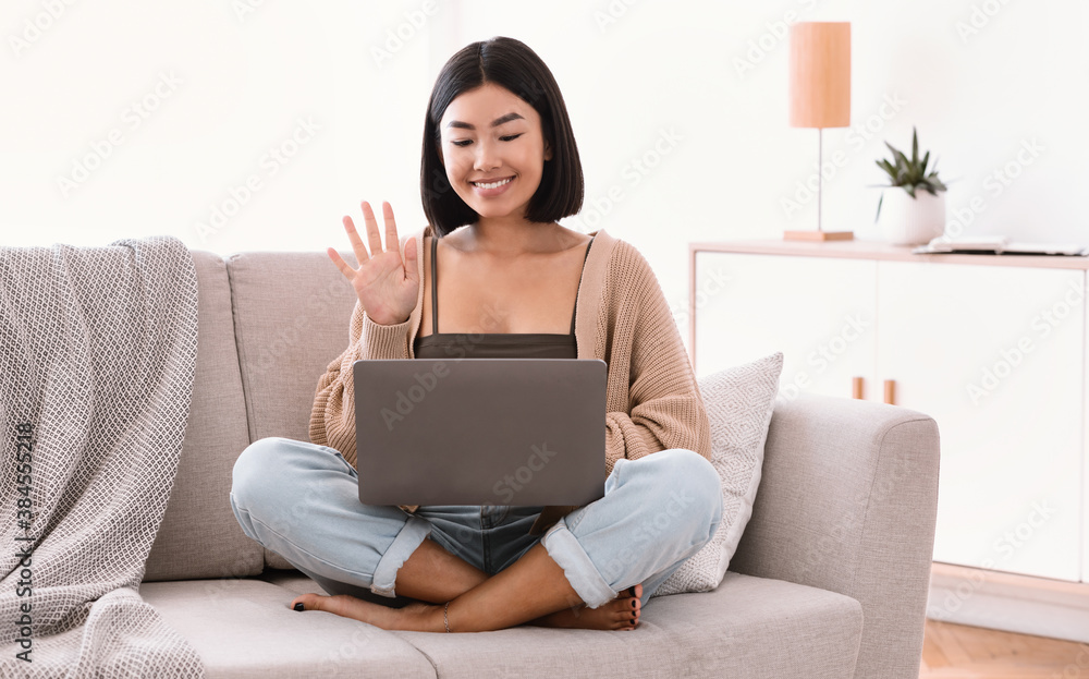 Happy woman using laptop for video call and waving