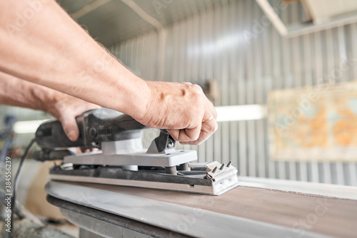 The mechanic works with a grinding tool. Sanding of car elements. Garage painting car service. Repairing car section after the accident.