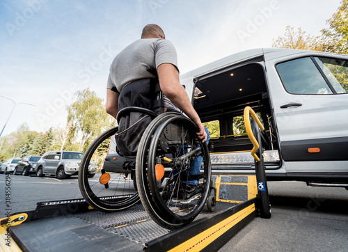Fotografering A man in a wheelchair moves to the lift of a specialized vehicle