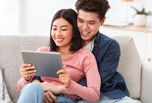 Happy Japanese Couple Using Digital Tablet Watching Movie At Home © Prostock-studio