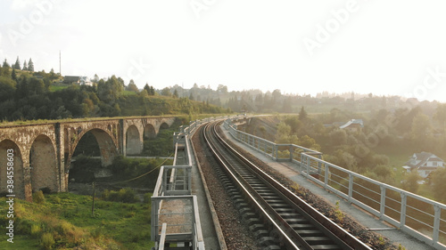 Industrial landscape with railroad and abandoned bridge. Countryside with huts on the background.