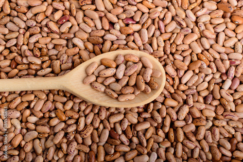 Top view of one wooden spoon in many fresh organic red beans in warm light, top view or flat lay of organic vegan food photographed with soft focus