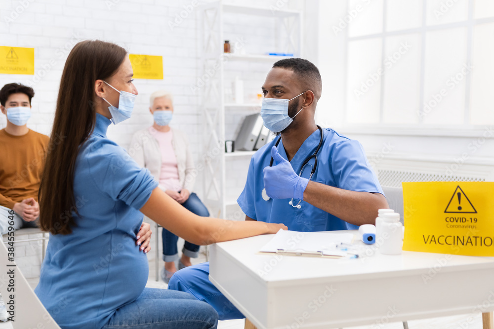 Fototapeta premium Doctor In Mask Gesturing Thumbs-Up To Vaccinated Patient In Hospital