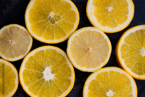 Sliced orange and lemon on black background. Citrus wallpaper.