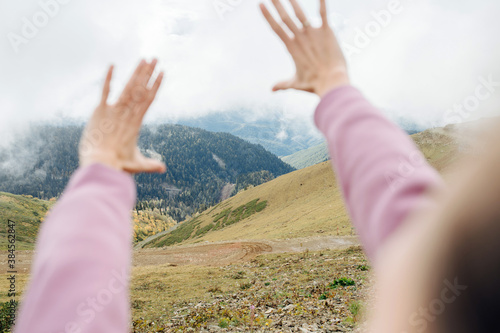 Point of view image of hands, taken high up in cloudy mountains.