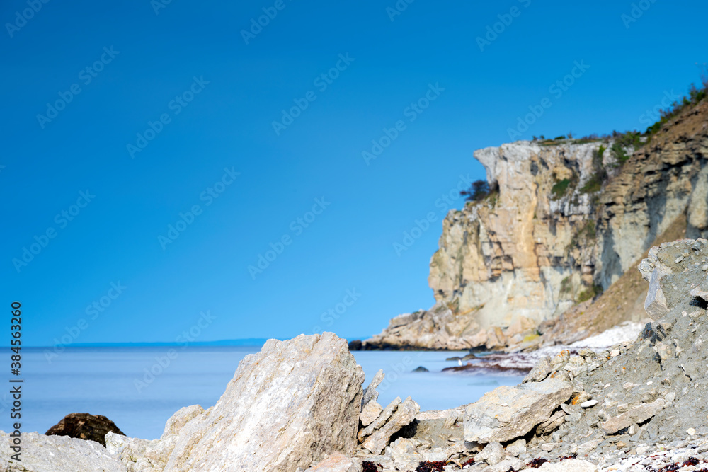 Limestone cliff next to ocean with boulders in foreground