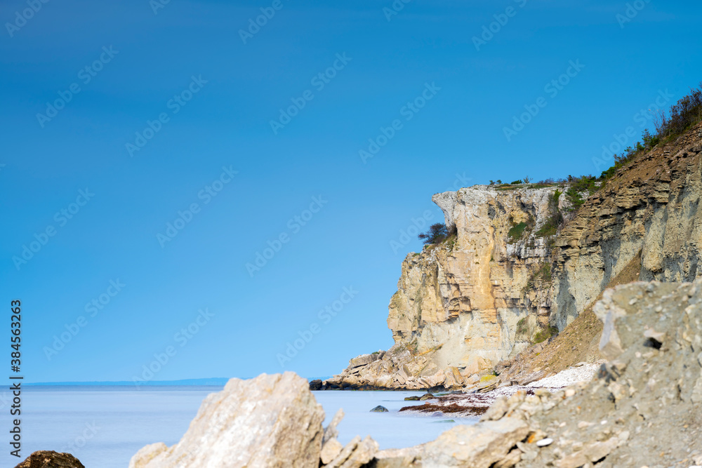 Limestone cliff next to ocean with boulders in foreground