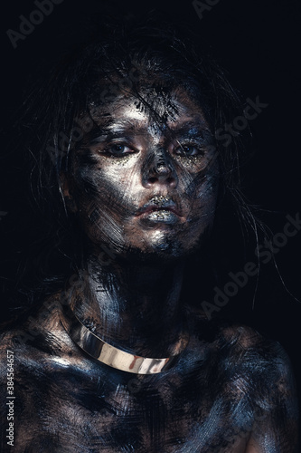 Fashion glamour portrait of a beautiful young caucasian woman. Bright messy black creative makeup. Dramatic dark image. The effect of a dirty face. Metal collar on the neck.