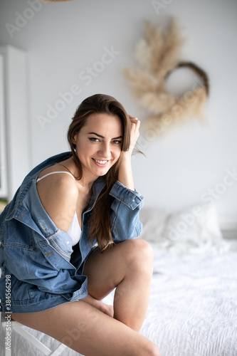 Smiling young woman relaxing at home. Brunette female wearing casual clothing and looking at camera.