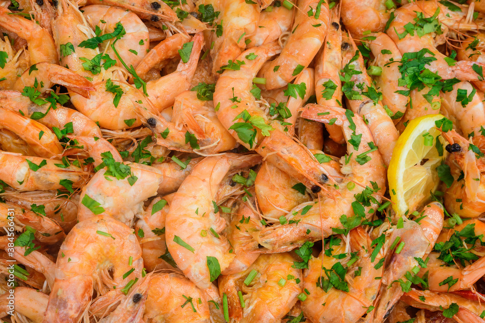 Close up of large portion of cooked shrimps with tomato sauce and green parsley in a large pan at a street food festival, ready to eat healthy seafood, beautiful orange monochrome outdoor background. Close up of large portion of cooked shrimps with tomato sauce and green parsley in a large pan at a street food festival, ready to eat healthy seafood, beautiful orange monochrome outdoor background.