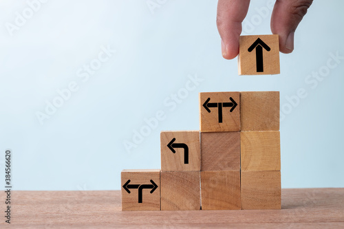 Business concept growth success process, Close up Businessman hand arranging wood cube with arrow stacking as step stair.