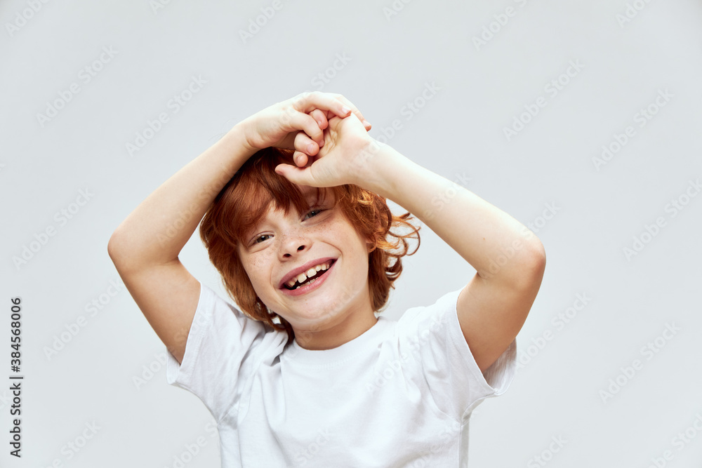 Redhead boy close-up smile hands over head white t-shirt cropped Redhead boy close-up smile hands over head white t-shirt cropped