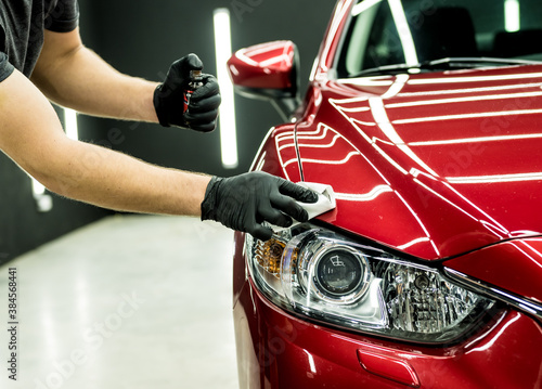 Car service worker applying nano coating on a car detail. © romaset