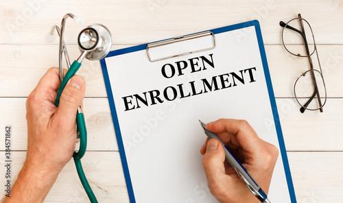 The doctor wrote - OPEN ENROLLMENT, stethoscope, glasses, pen