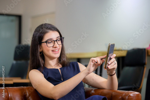 Cheerful casual woman taking selfie relaxing in modern office