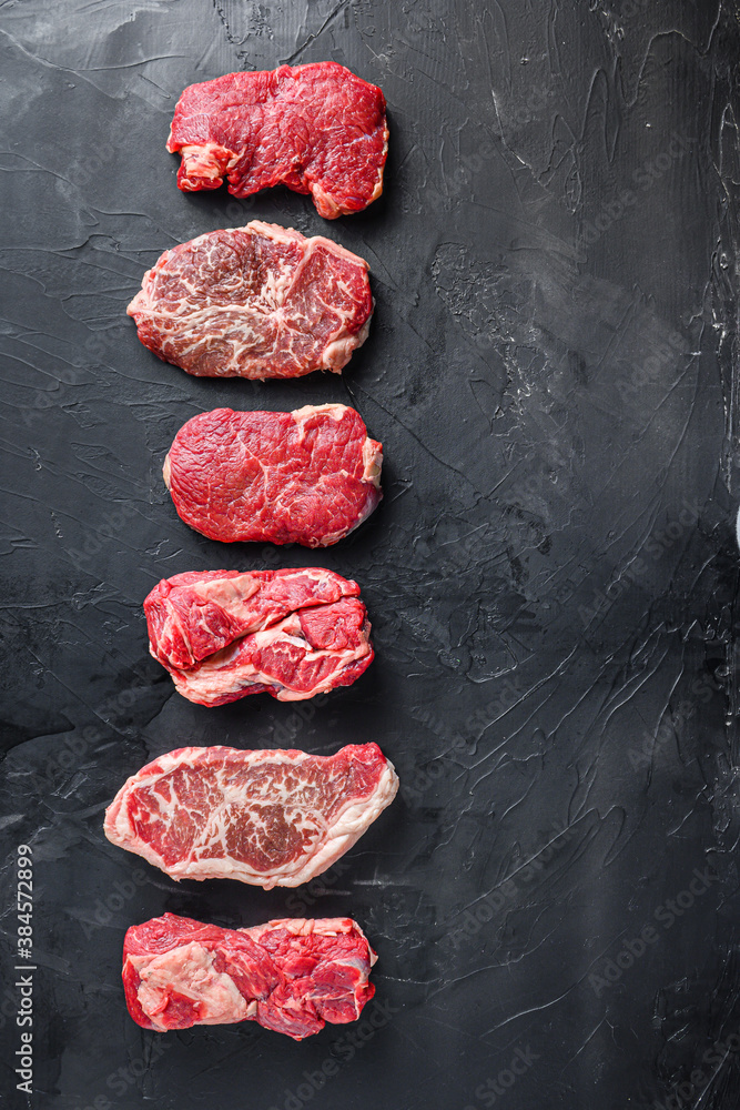 Raw set of rump, top blade, chuck roll beef steak cut, on black textured background, top view with space for text.