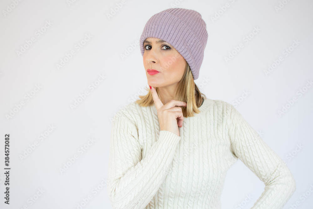 Image of thoughtful pensive cute young woman standing isolated over white background in studio, looking aside, putting hand close to face, wearing warm clothes. Copy space for advertisement. Image of thoughtful pensive cute young woman standing isolated over white background in studio, looking aside, putting hand close to face, wearing warm clothes. Copy space for advertisement.
