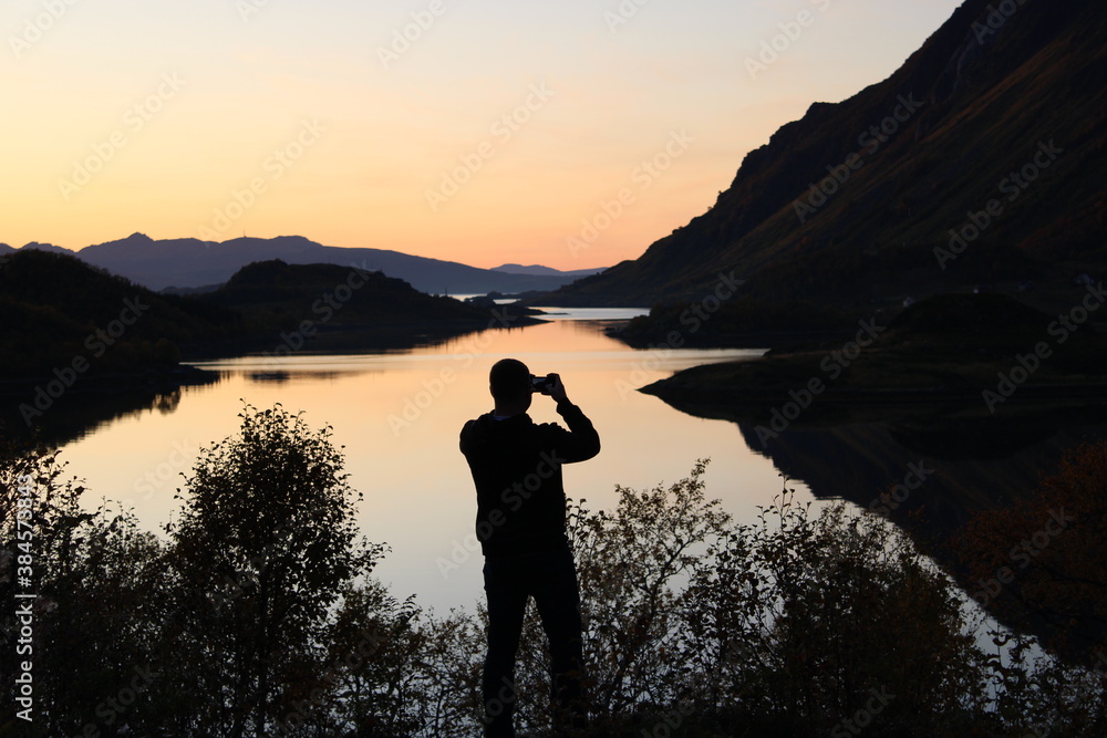 Man taking photos of the sunset on Lofoten islands in Norway Man taking photos of the sunset on Lofoten islands in Norway
