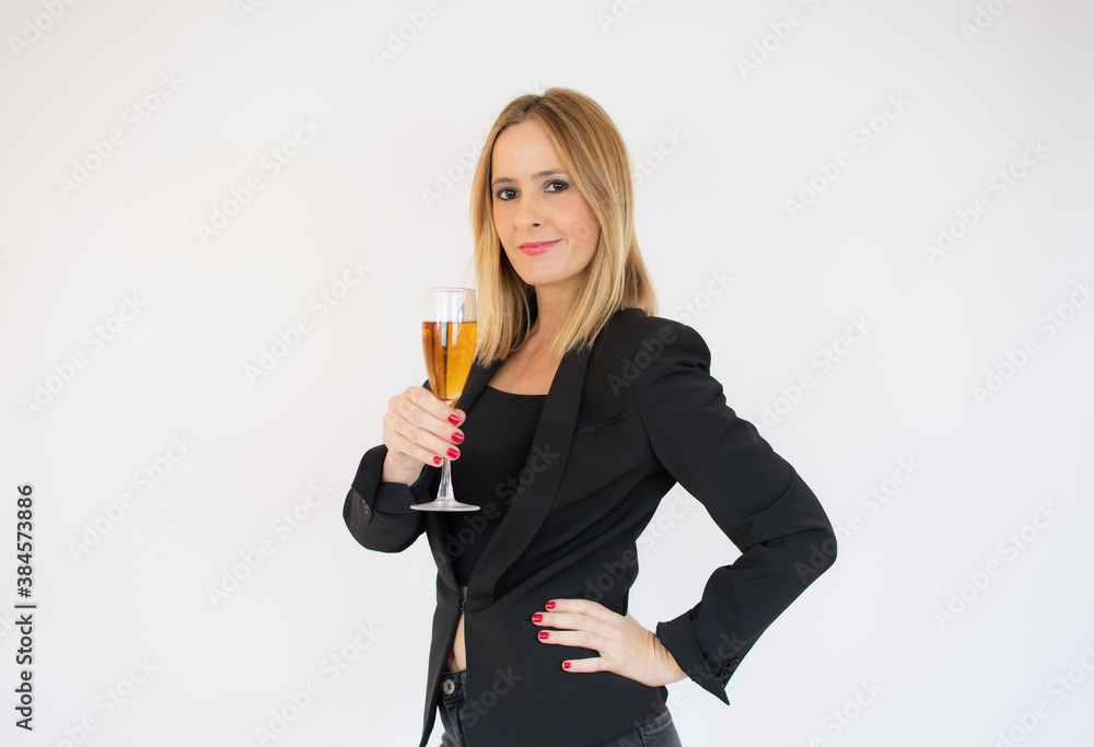 Young and beautiful woman standing with glass of champagne and smiling. Woman is happy about the New Year