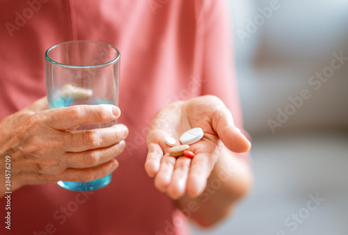 woman holding pill and glass of fresh water