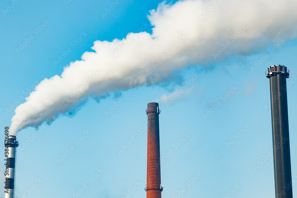 Chimney smoke at factory against blue sky